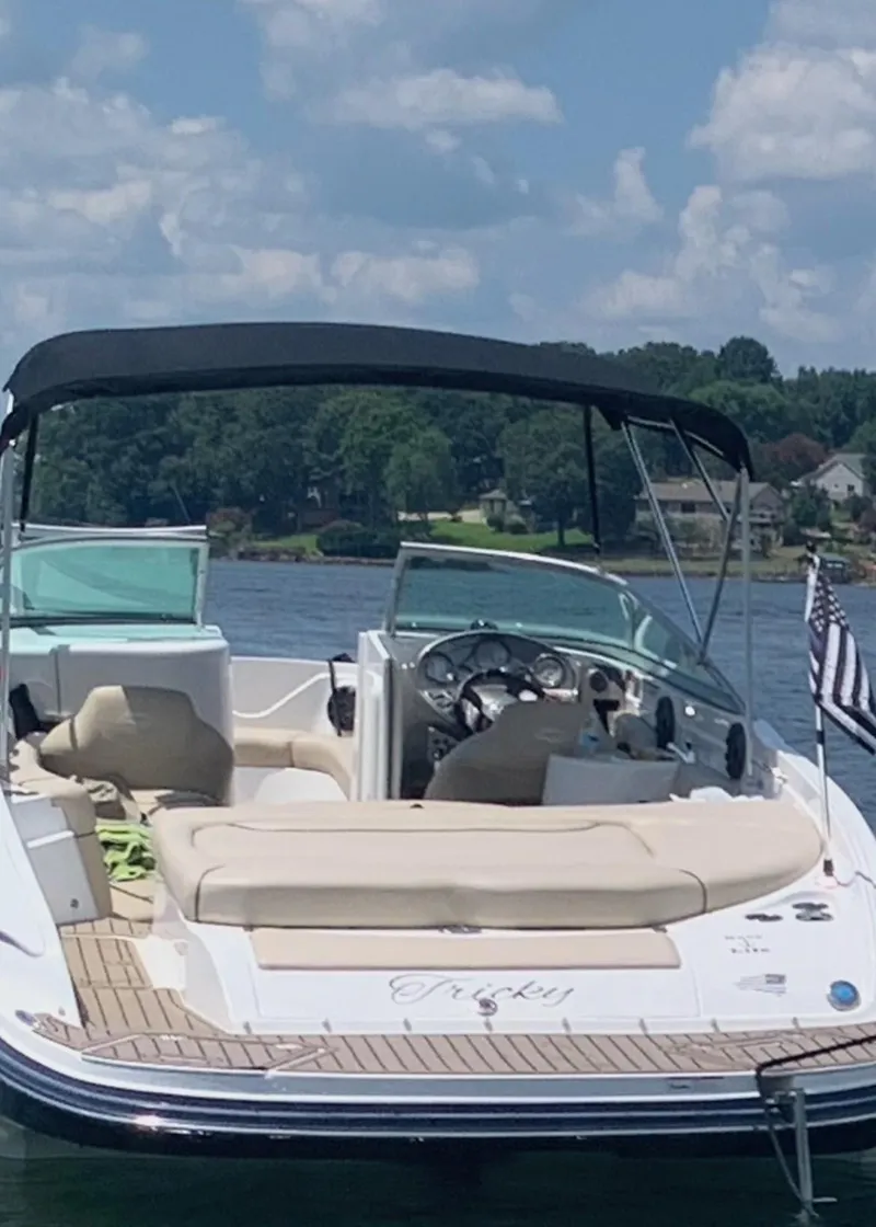 Slide: The Image of 2014 Rinker 246 Captiva Bowrider on a lake with a black canopy. - 3