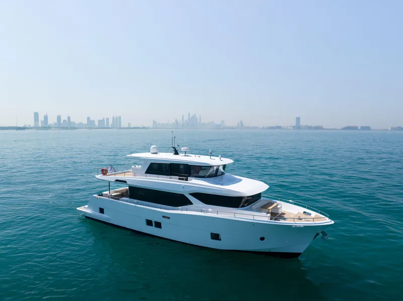 The Image of 2025 Nomad 70 SUV yacht cruising on calm waters with city skyline in background. - 1