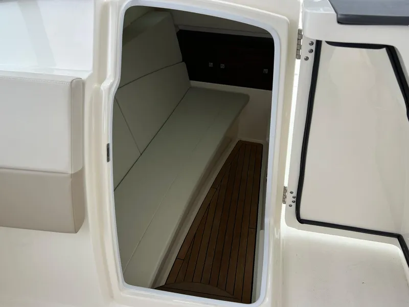 Slide: The Image of 2018 Boston Whaler 320 Vantage cabin interior with cushioned seating and wooden flooring. - 5