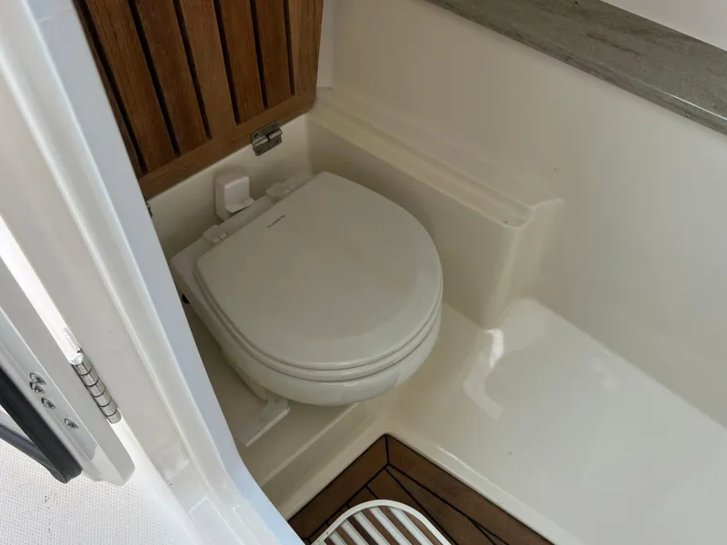 Slide: The Image of 2018 Boston Whaler 320 Vantage boat bathroom with toilet and wooden accents. - 7