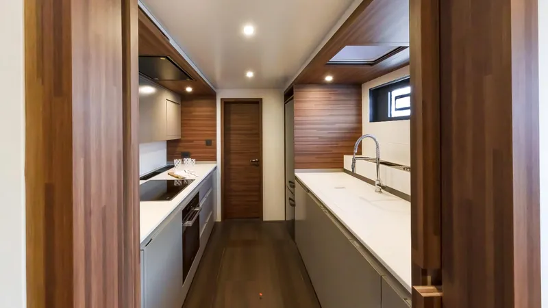 Slide: The Image of Modern kitchen interior on 2025 Fountaine Pajot Thira 80 yacht, featuring sleek wood finishes. - 24