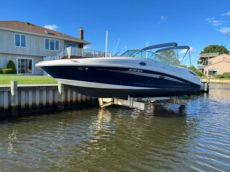 Slide: The Image of 2011 Sea Ray 300 Sundeck boat docked by waterfront homes under clear blue sky. - 0