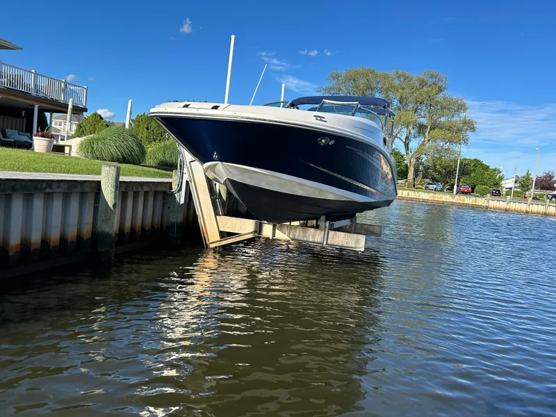 Slide: The Image of 2011 Sea Ray 300 Sundeck boat docked by a waterfront under a clear blue sky. - 1