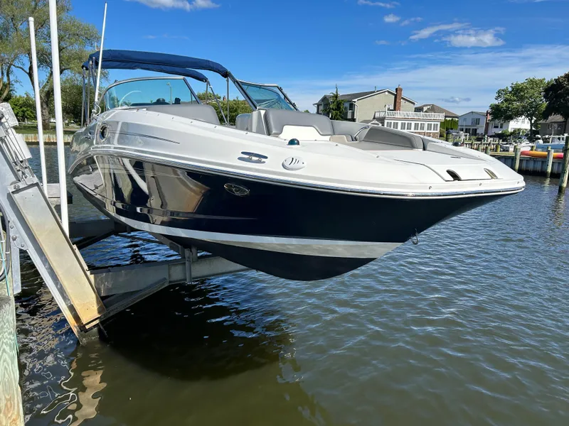 Slide: The Image of 2011 Sea Ray 300 Sundeck boat on lift, docked by waterfront homes. - 2