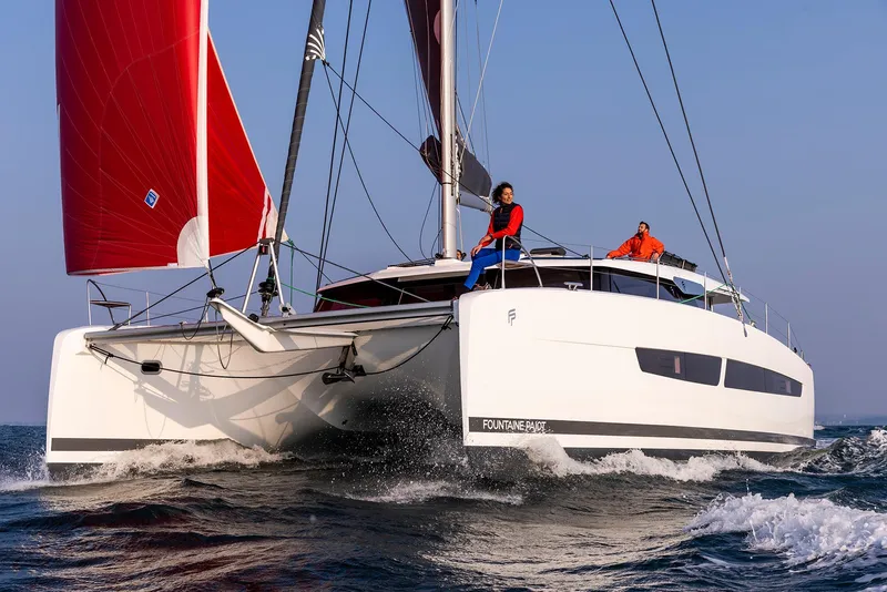 Slide: The Image of 2025 Fountaine Pajot Aura 51 catamaran sailing with red sails on open water. - 8