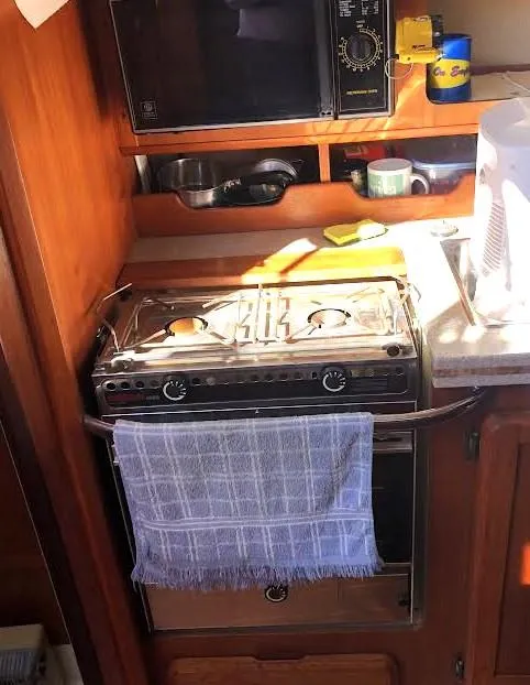 Slide: The Image of 1990 Hunter Vision 32 yacht kitchen with stove, microwave, and wooden cabinetry. - 14