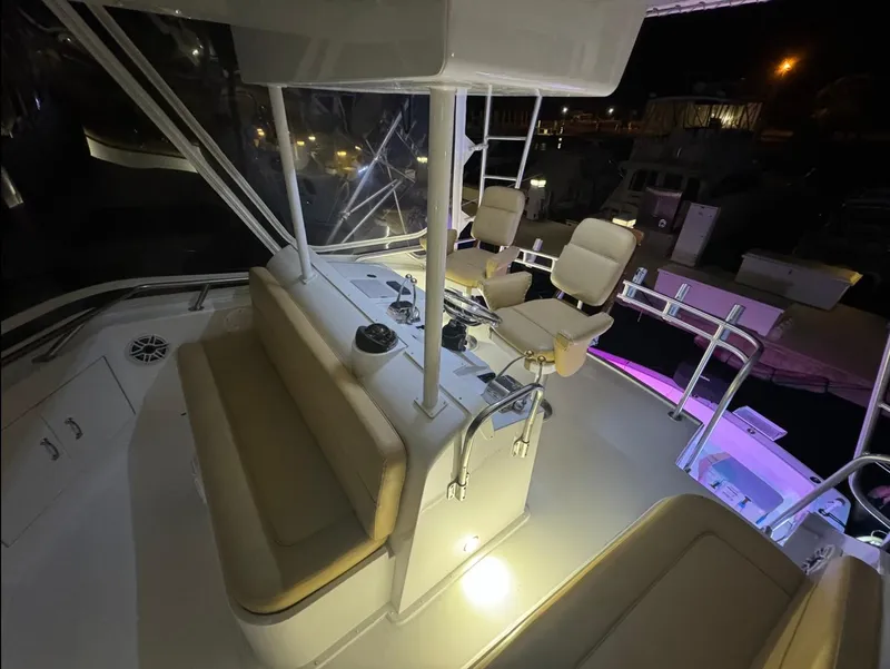 Slide: The Image of 1990 Hatteras 45 Convertible yacht cockpit with seating and controls, illuminated at night. - 11
