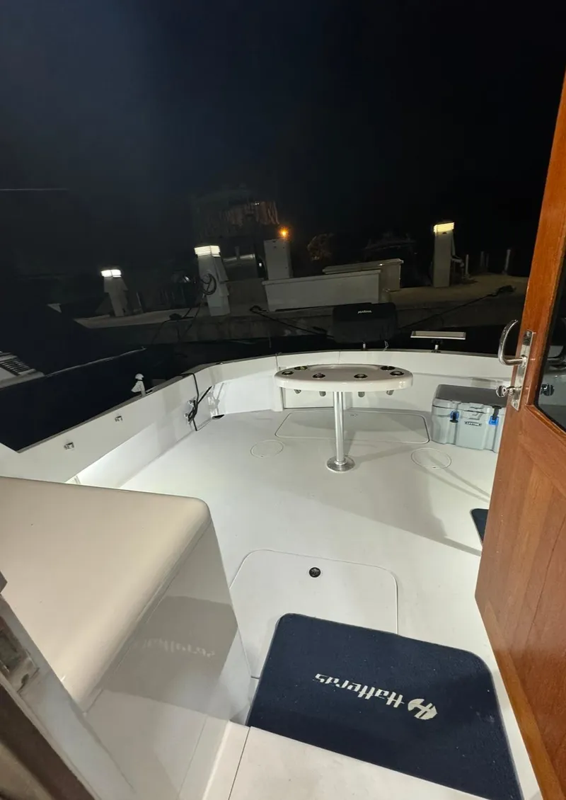 Slide: The Image of 1990 Hatteras 45 Convertible boat deck at night, featuring seating and fishing equipment. - 15