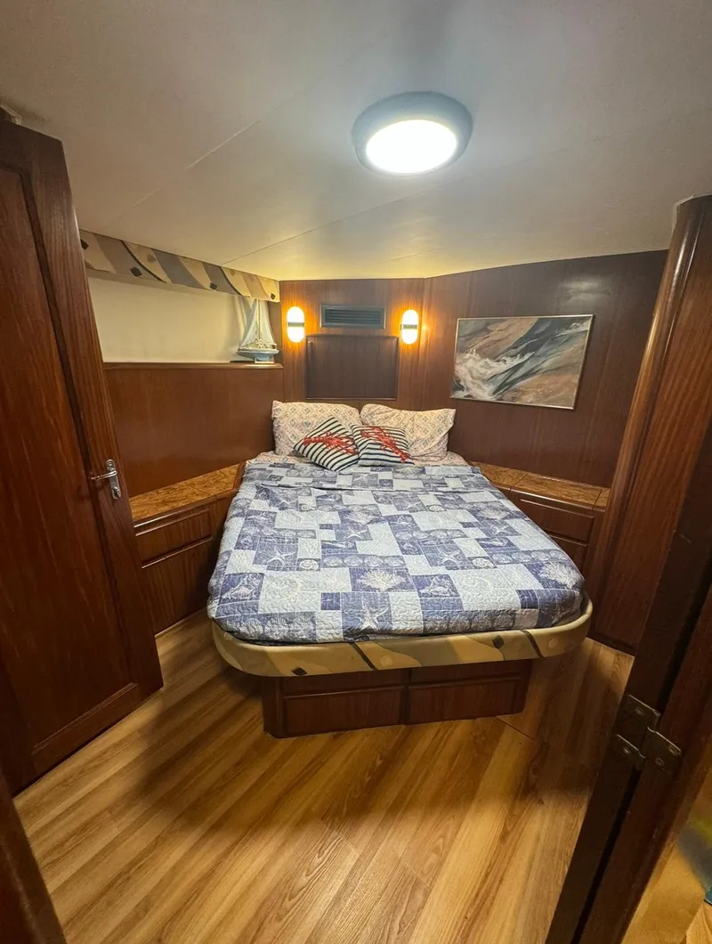 Slide: The Image of Cozy bedroom in 1990 Hatteras 45 Convertible yacht with wood paneling and quilted bedding. - 20