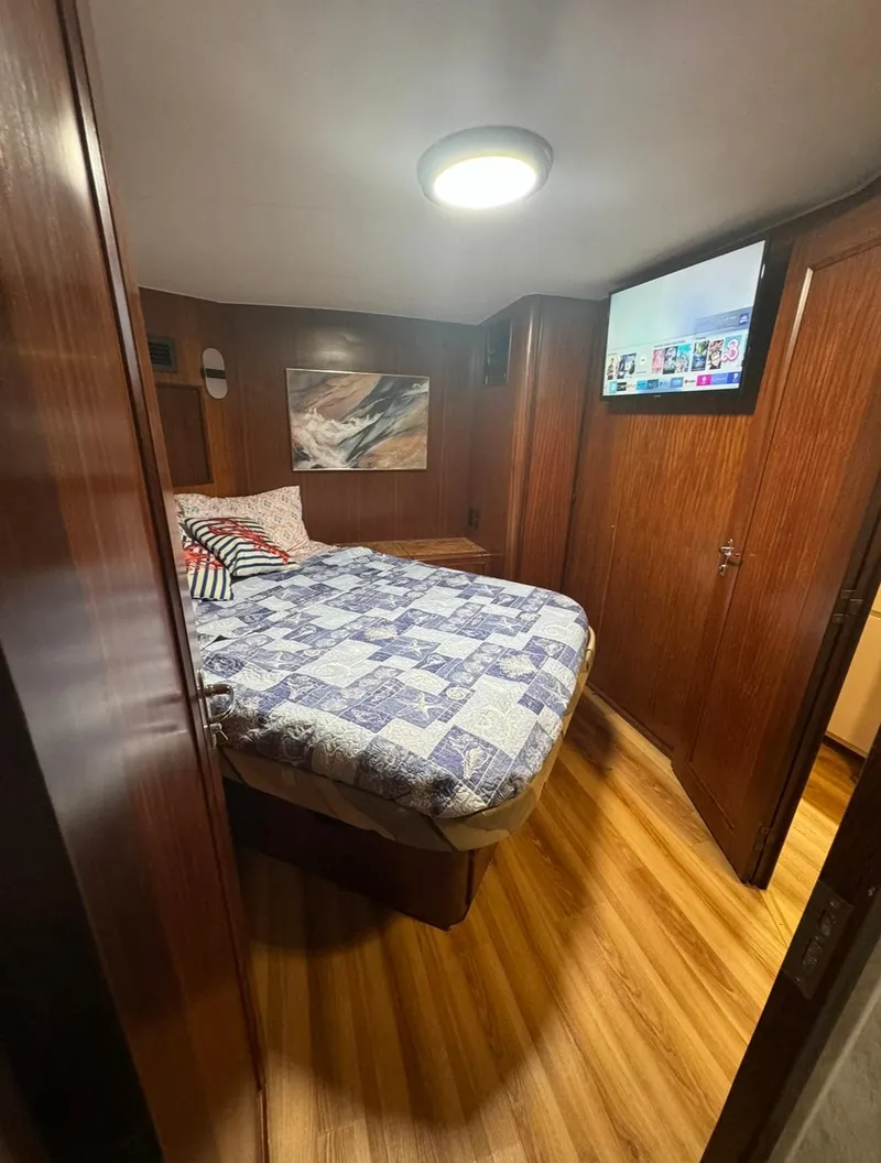 Slide: The Image of Cozy bedroom in 1990 Hatteras 45 Convertible yacht with wood paneling and modern TV. - 21