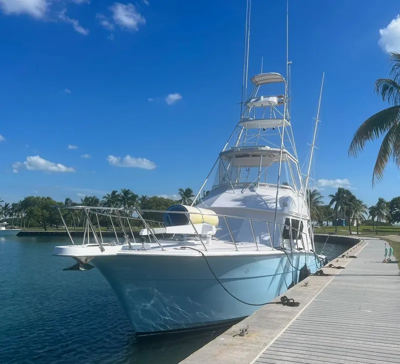 Slide: The Image of 1990 Hatteras 45 Convertible yacht docked by palm trees under a clear blue sky. - 3