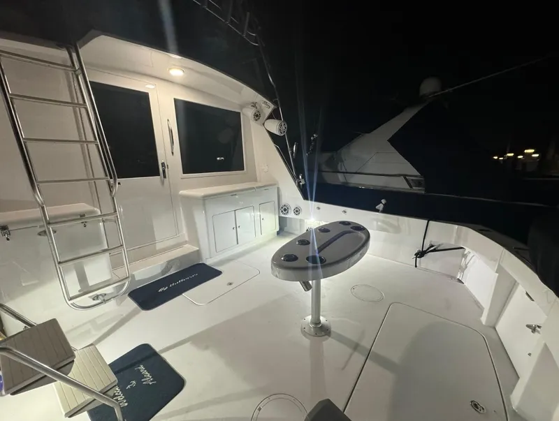 Slide: The Image of 1990 Hatteras 45 Convertible yacht deck at night, featuring ladder and fishing station. - 31