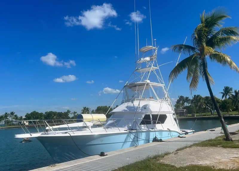 Slide: The Image of 1990 Hatteras 45 Convertible yacht docked by palm trees under a clear blue sky. - 4