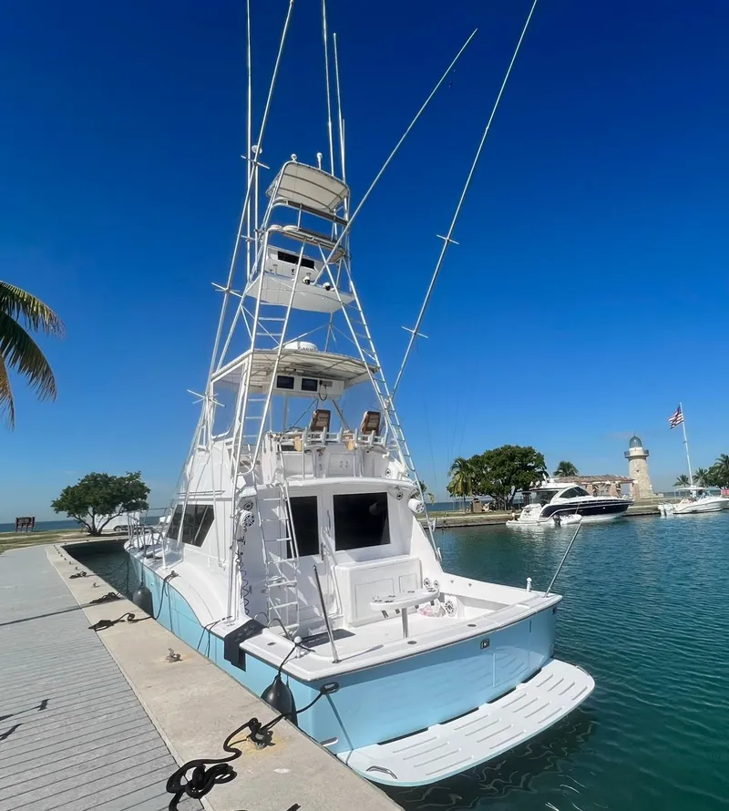 Slide: The Image of 1990 Hatteras 45 Convertible yacht docked at marina under clear blue sky. - 6