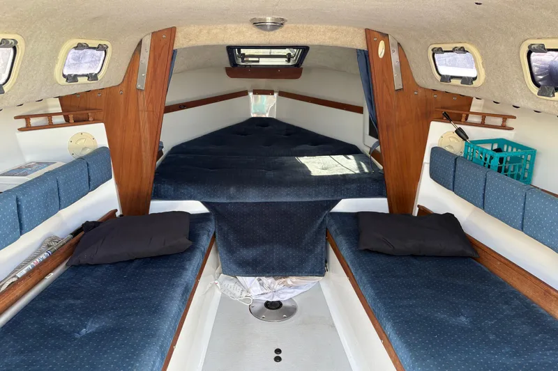 Slide: The Image of Interior of a 2002 Precision 23 sailboat with blue cushioned seating and wooden accents. - 12