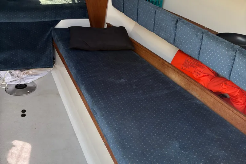 Slide: The Image of Interior of a 2002 Precision 23 sailboat with blue cushions and a life jacket. - 14