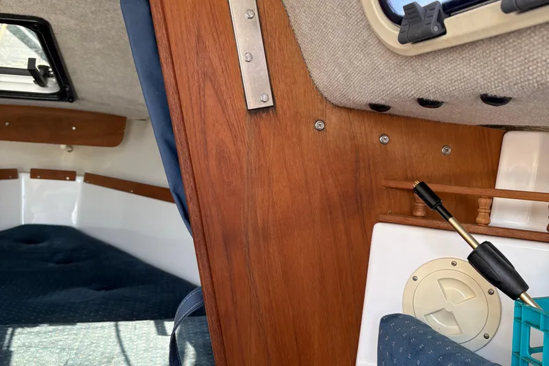 Slide: The Image of Interior of a 2002 Precision 23 sailboat, featuring wood paneling and seating area. - 16