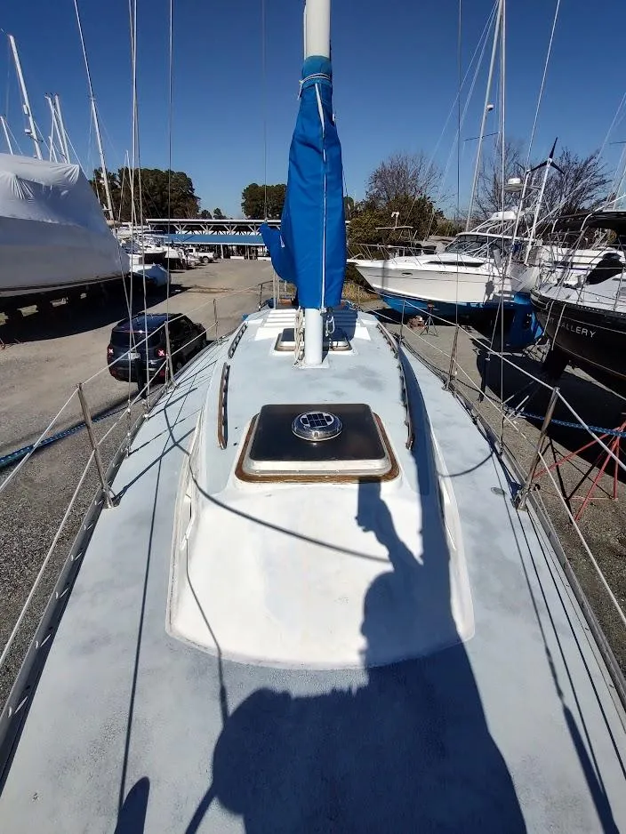 Slide: The Image of 1979 Endeavour 32 sailboat on dry dock, showcasing deck and mast under clear blue sky. - 18