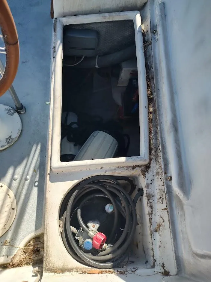 Slide: The Image of Open storage compartment on 1979 Endeavour 32 sailboat deck, showing cables and equipment. - 28