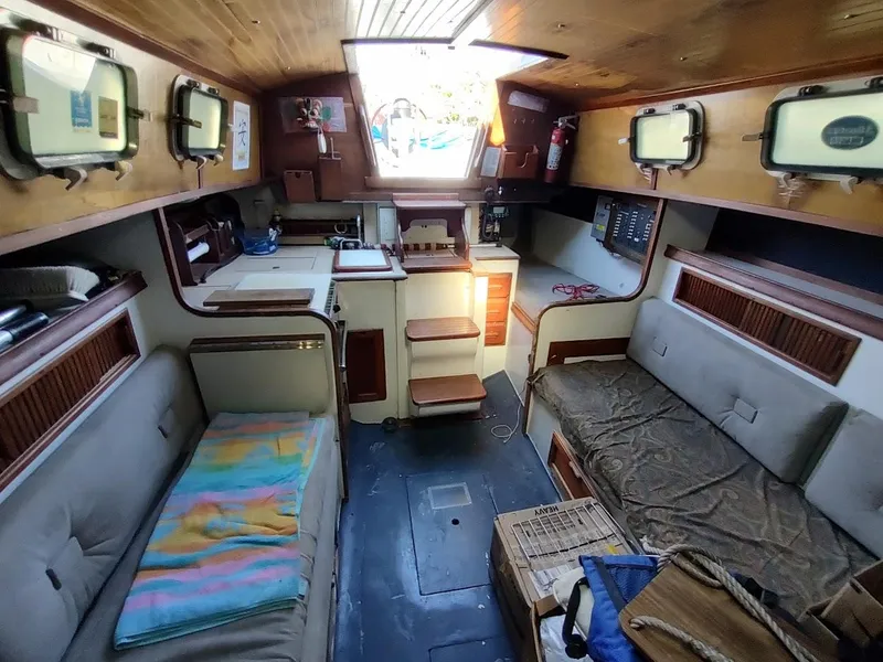 Slide: The Image of Interior of a 1979 Endeavour 32 sailboat, featuring cozy seating and wooden cabinetry. - 35