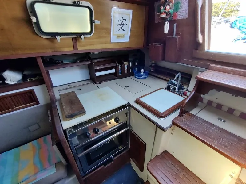 Slide: The Image of 1979 Endeavour 32 sailboat galley with stove, sink, and wooden cabinetry. - 36