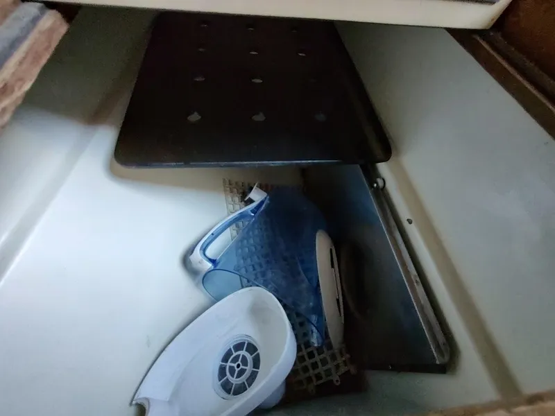 Slide: The Image of Storage compartment with a blue pitcher and white lid inside a 1979 Endeavour 32 boat. - 40
