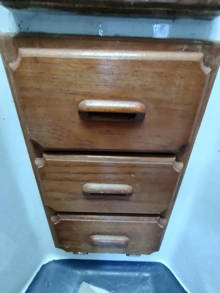 Slide: The Image of Wooden drawers inside a 1979 Endeavour 32 boat, featuring three handles. - 44