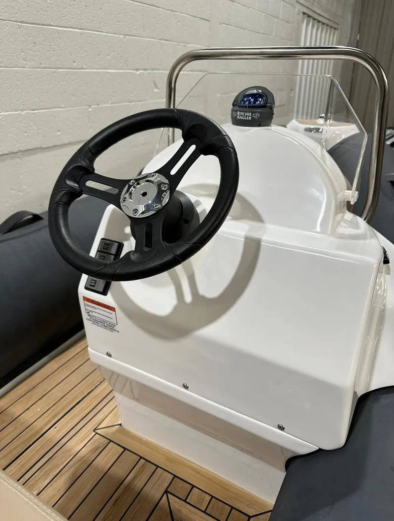 Slide: The Image of 2024 Apex A-12 Deluxe Tender steering console with black wheel and wooden deck. - 7