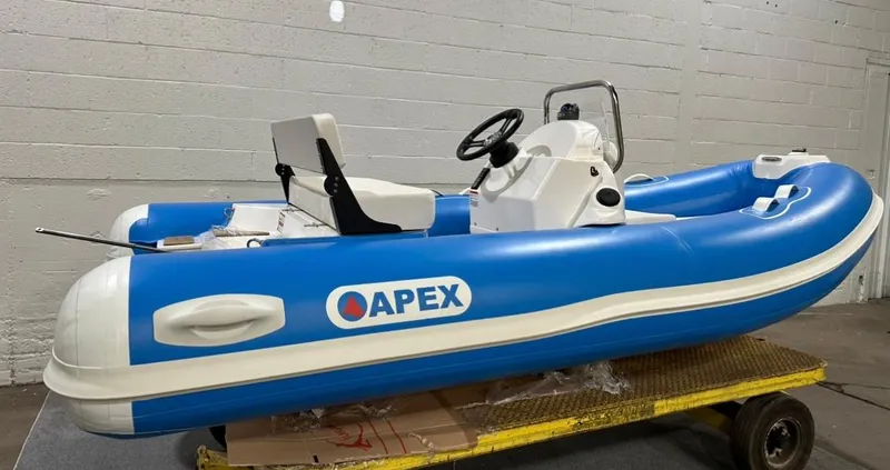 Slide: The Image of 2024 Apex A-12 Deluxe Tender, blue and white inflatable boat, displayed indoors. - 10