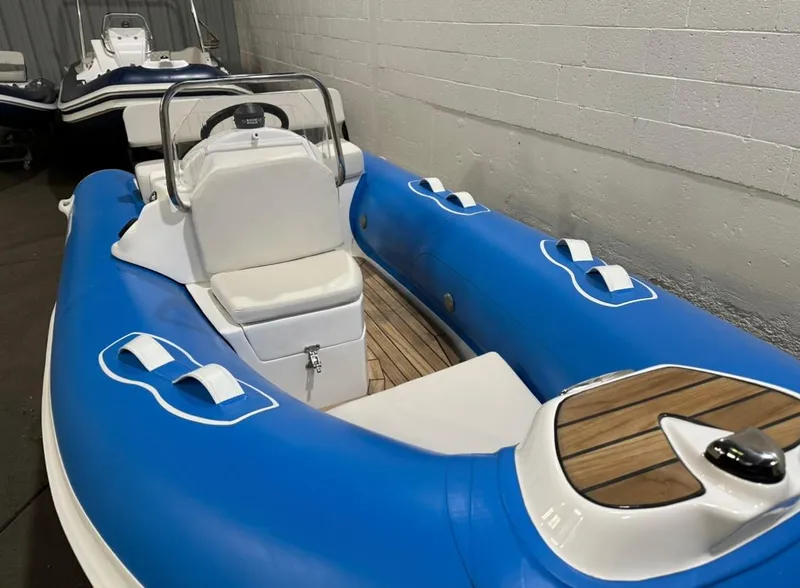 Slide: The Image of 2024 Apex A-12 Deluxe Tender, blue inflatable boat with white seating and wooden accents. - 11