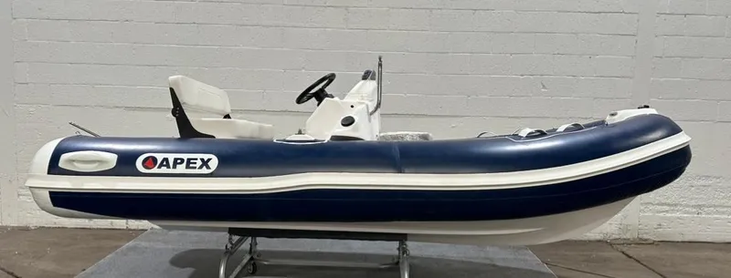 The Image of 2024 Apex A-13 Deluxe Tender boat, blue and white, displayed indoors. - 0