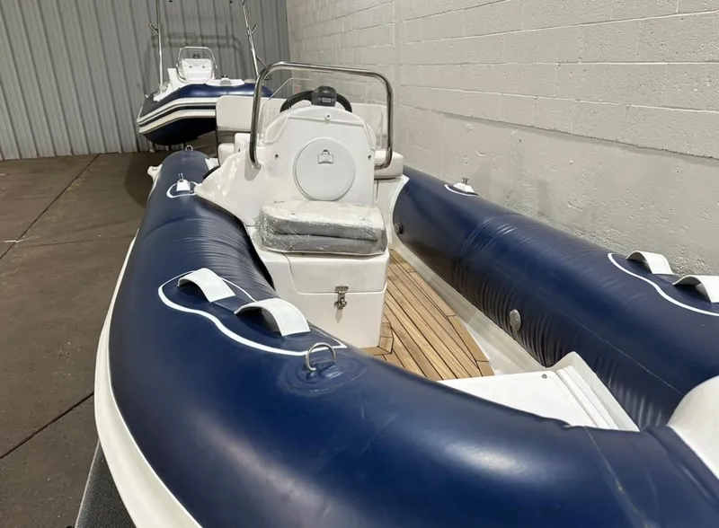 Slide: The Image of 2024 Apex A-13 Deluxe Tender boat with blue and white design in storage. - 5