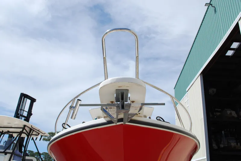 Slide: The Image of 1996 Regulator 26 Classic boat with a red hull and anchor, docked near a warehouse. - 5