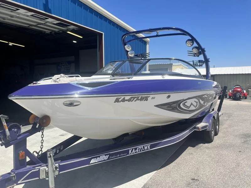 Slide: The Image of 2007 Malibu 247 LSV boat on trailer outside blue building. - 4