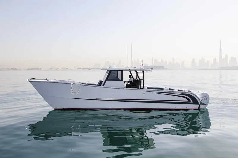 Slide: The Image of 2025 Custom SilverCAT 40CC boat on calm water with city skyline in background. - 24