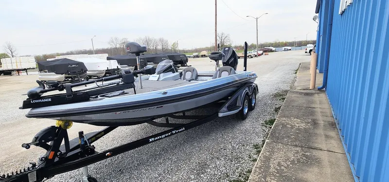 Slide: The Image of 2022 Ranger Z519 boat on trailer, parked outdoors near a blue building. - 2