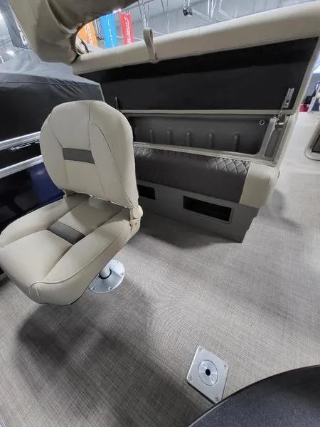 Slide: The Image of 2024 Sun Tracker Fishin Barge 20 DLX interior with beige seating and storage compartments. - 6