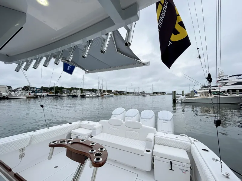 Slide: The Image of 2025 HCB 48 Campeon boat interior at marina, featuring seating and fishing rod holders. - 43