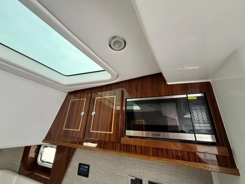 Slide: The Image of Modern kitchen area in 2025 HCB 48 CAMPEON boat with microwave and wooden cabinets. - 68