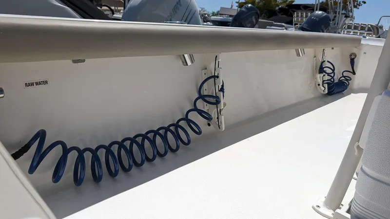 Slide: The Image of 2023 Key West 250 Bay Reef boat deck with blue coiled hoses and raw water outlets. - 15