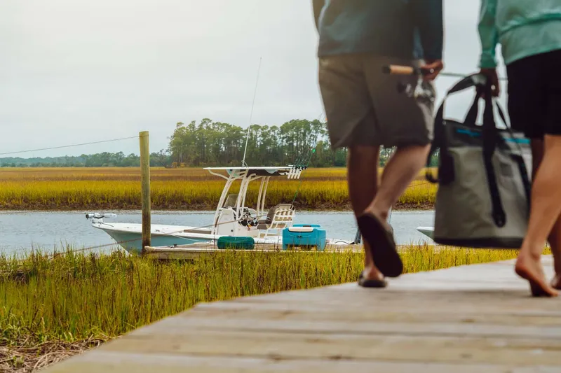 Slide: The Image of Couple walking towards 2023 Key West 250 Bay Reef boat docked by marshland. - 40