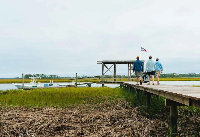 Slide: The Image of 2023 Key West 250 Bay Reef boat docked near marshland with people walking on pier. - 42