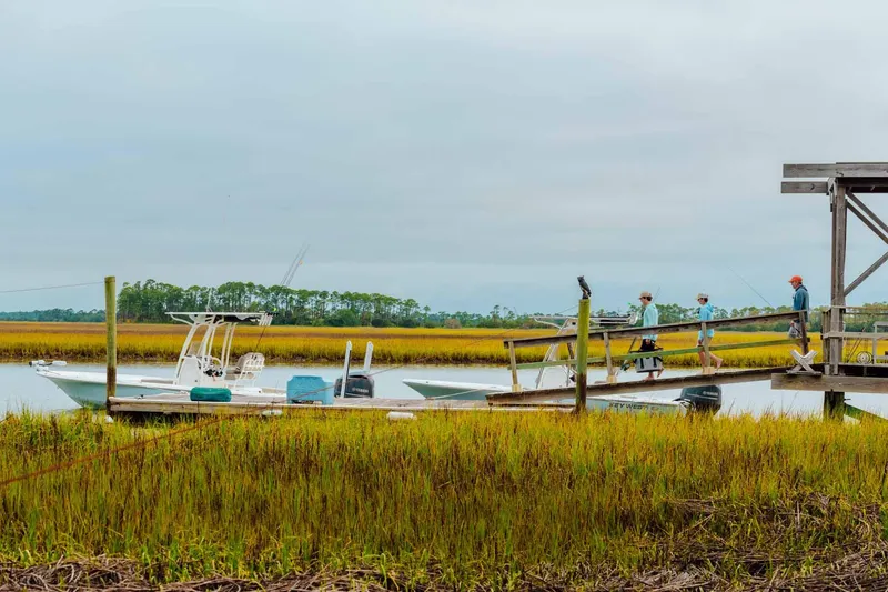 Slide: The Image of 2023 Key West 250 Bay Reef boat docked near marshland with people on pier. - 48