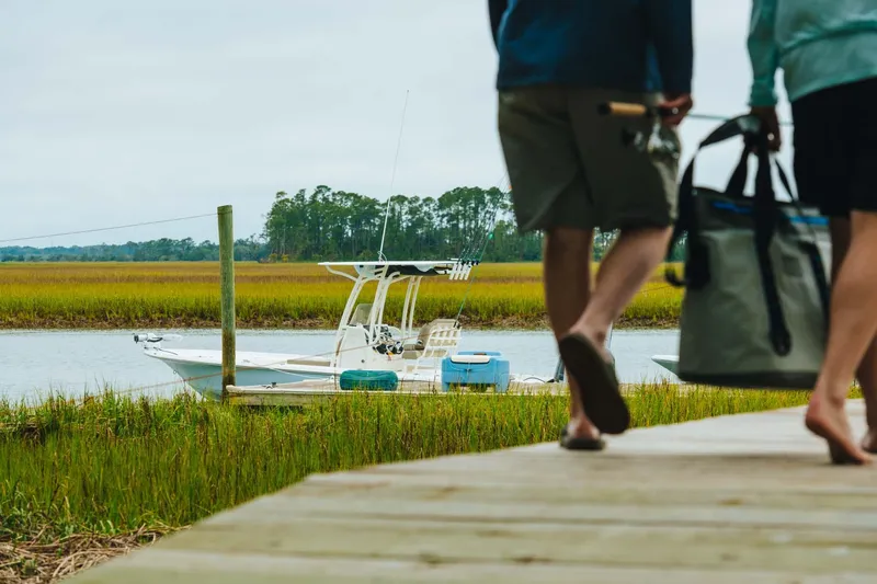 Slide: The Image of 2023 Key West 250 Bay Reef boat docked in marshland, people walking on wooden pier. - 50