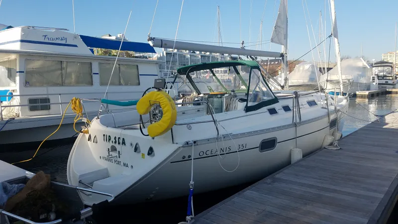 Slide: The Image of 1995 Beneteau Oceanis 351 sailboat docked at marina, featuring a white hull and yellow lifebuoy. - 28