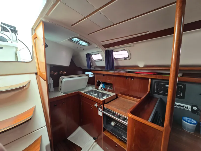 Slide: The Image of Interior of 1995 Beneteau Oceanis 351 sailboat, featuring a compact kitchen area. - 9