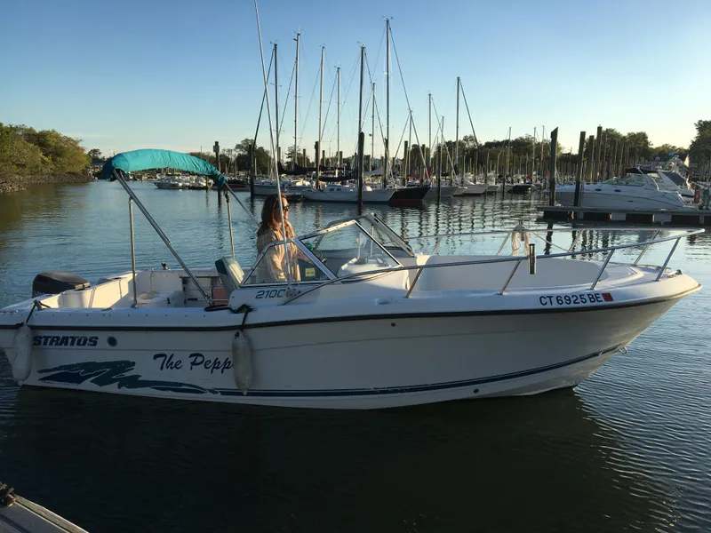 Slide: The Image of 1998 Stratos 2100 boat docked in a marina with sailboats in the background. - 2