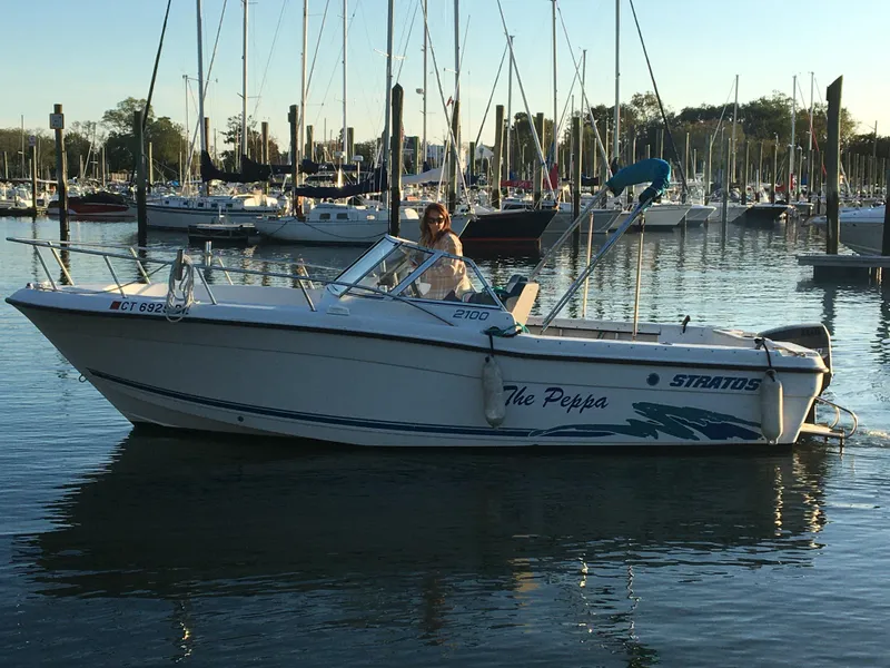Slide: The Image of 1998 Stratos 2100 boat docked in a marina with sailboats in the background. - 6