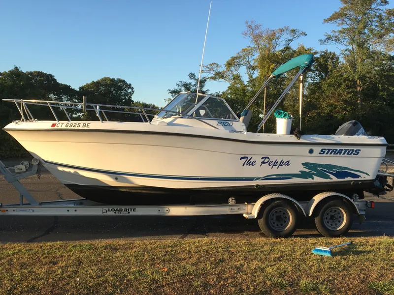 Slide: The Image of 1998 Stratos 2100 boat on trailer, named The Peppa, parked outdoors. - 8