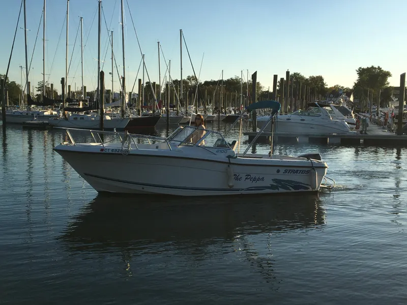 Slide: The Image of 1998 Stratos 2100 boat cruising in a marina with sailboats in the background. - 4